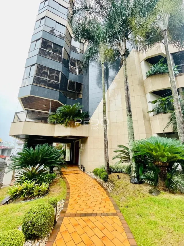 Vista da fachada de um edifício residencial em Lajeado, Brasil, com paisagismo tropical.