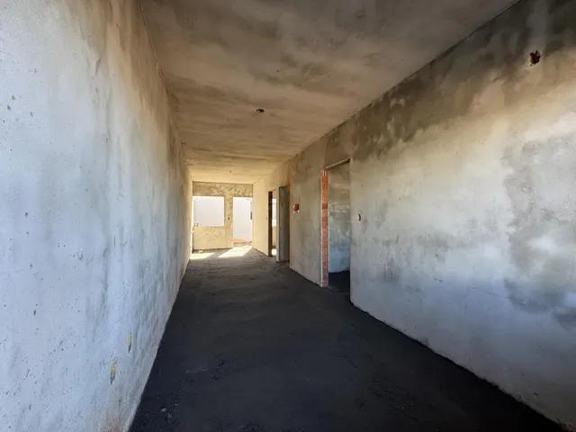Corredor longo e sem acabamento em uma residência.