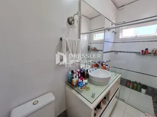 Foto de um banheiro com azulejos brancos e louças sanitárias.