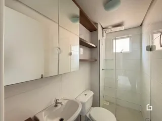 Banheiro com box de vidro e revestimento branco.
