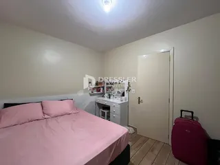 Quarto com cama rosa e armário branco.
