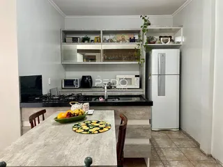 Foto de uma cozinha com armários e uma mesa de madeira em um imóvel no Brasil.