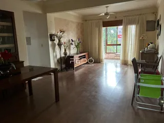 Sala de estar com piso de madeira e grandes janelas em um imóvel no Brasil.