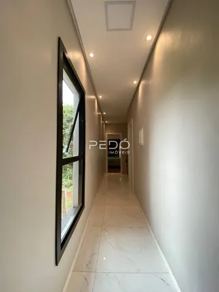 Corredor interno de um imóvel com paredes brancas e piso claro.