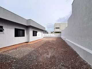 Vista externa de um pátio de cascalho entre duas construções.