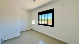 Ambiente interno com paredes brancas e uma grande janela que oferece uma vista externa.