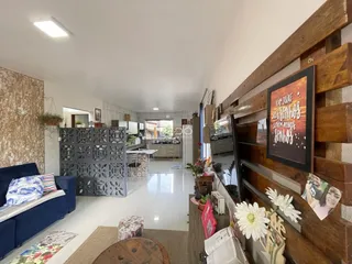Sala de estar com piso de cerâmica e paredes de madeira na residência.