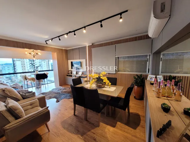 Sala de estar com vista para a cidade e piso de madeira.