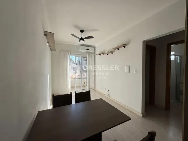 Interior de uma sala com paredes brancas e piso de madeira clara.