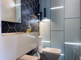 Foto de um banheiro mostrando a bancada branca e o vaso sanitário.