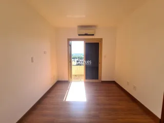 Interior de um ambiente com piso de madeira e parede branca.