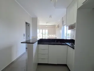 Cozinha moderna com armários brancos e bancada escura.