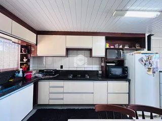 Foto de uma cozinha moderna com armários brancos e bancadas escuras.