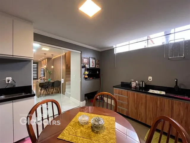 Vista de uma sala de jantar com mesa de madeira no interior de uma residência.