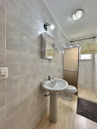 Foto do interior de um banheiro com revestimento de azulejos brancos.