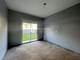 Ambiente interno com paredes cinzas e piso de concreto em uma residência.