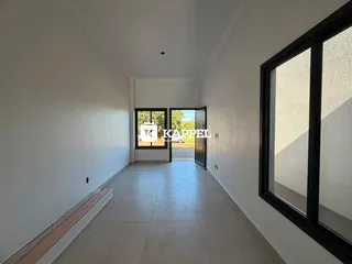 Hall de corredor com paredes brancas e piso claro, com portas de vidro no final.