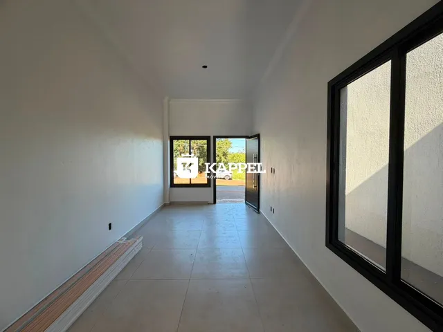 Hall de corredor com paredes brancas e piso claro, com portas de vidro no final.
