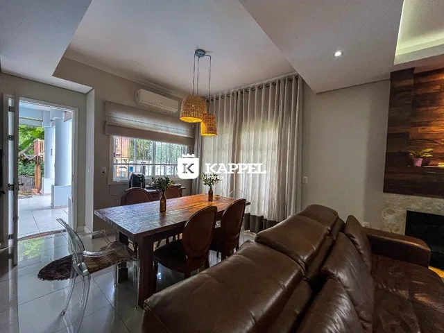Sala de jantar com mesa de madeira e cortinas claras.