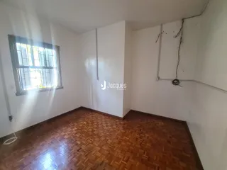 Interior de uma sala com piso de madeira e janela.