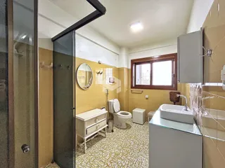 Foto de um banheiro interno com azulejos amarelos e piso estampado.