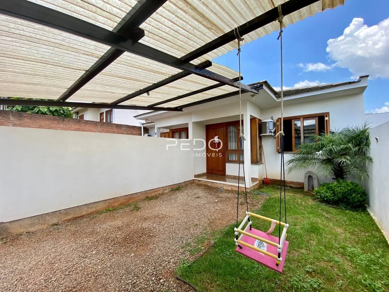 Vista externa de uma residência com área de lazer coberta e jardim.
