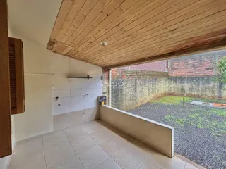 Interior de uma área com teto de madeira e vista para o quintal.