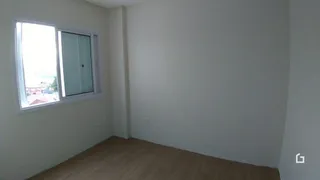 Vista interna de um cômodo com janela e piso de madeira.