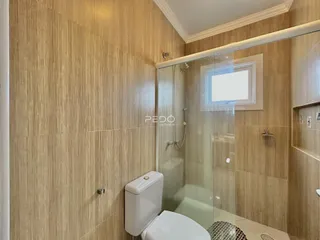 Foto de um banheiro com revestimento de cerâmica e box de vidro.