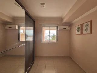 Interior de um corredor com janela e paredes claras.