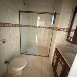 Foto de um banheiro com box de vidro e revestimento de azulejos brancos.
