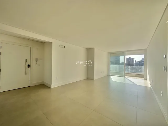 Vista interna de um espaço amplo com paredes brancas e piso claro.