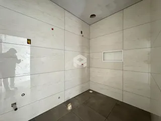 Parede interna com revestimento cerâmico e piso de concreto em um ambiente.