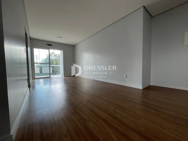 Interior com piso de madeira clara e paredes brancas em um imóvel.
