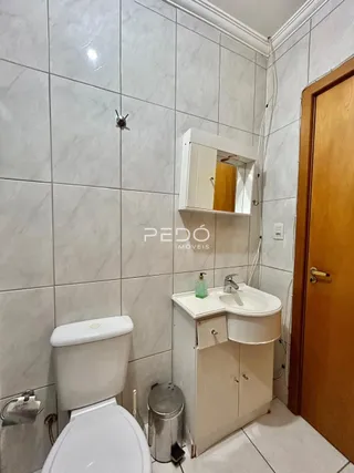 Foto de um banheiro com azulejos brancos e louças sanitárias.