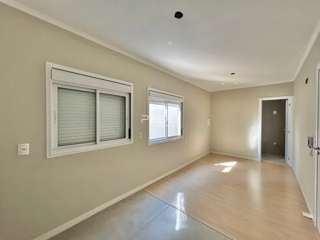 Uma sala de estar com piso de madeira clara e paredes bege.