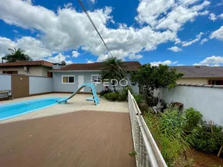 A foto mostra a área externa com piscina e escorregador de uma residência.