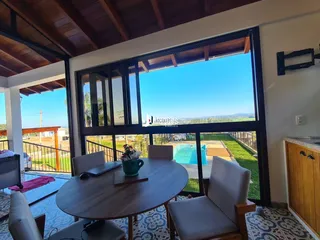 Vista da sala de jantar com vista para a piscina e jardim.