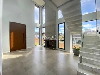 Sala de estar com grandes janelas e escadaria de mármore em um imóvel em Lajeado.
