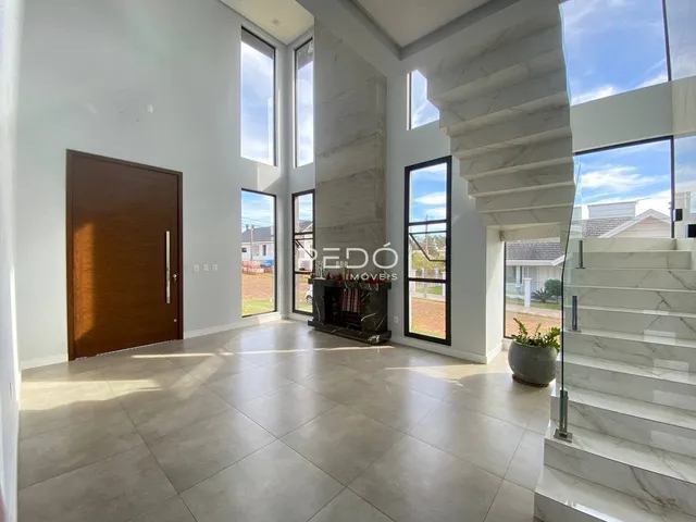 Sala de estar com grandes janelas e escadaria de mármore em um imóvel em Lajeado.