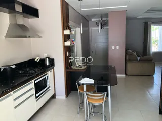 Ambiente de sala de estar e cozinha com mesa de jantar em apartamento.