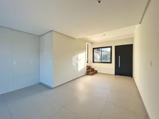 Vista interna de uma área ampla com piso de cerâmica e paredes brancas.