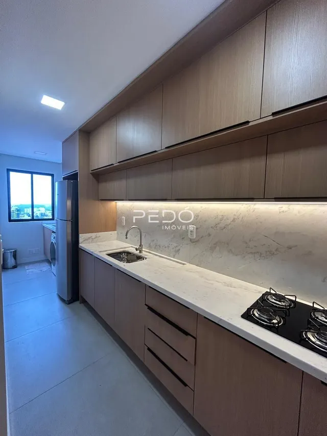 Cozinha moderna com armários de madeira e bancadas claras.