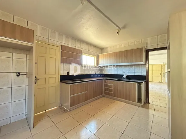 Cozinha com armários de madeira e piso cerâmico claro.