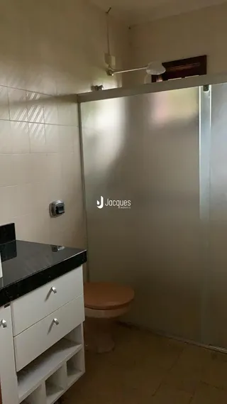 Vista de um banheiro com bancada escura e armários brancos.