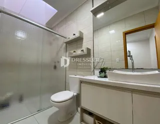 Banheiro com box de vidro e bancada branca.