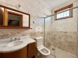 Foto de um banheiro com azulejos brancos e box de vidro.