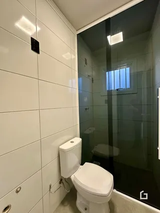 Foto de um banheiro com azulejos brancos e box de vidro.