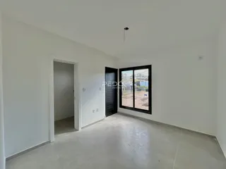 Interior de uma sala com paredes brancas e piso de concreto.