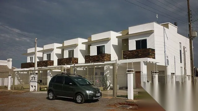 Fachada de uma casa branca em Lajeado, Brasil, com cerca frontal.